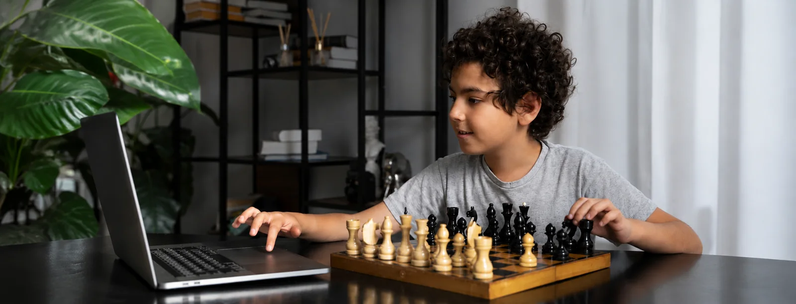 A student playing chess at a laptop during a ChessCurve session